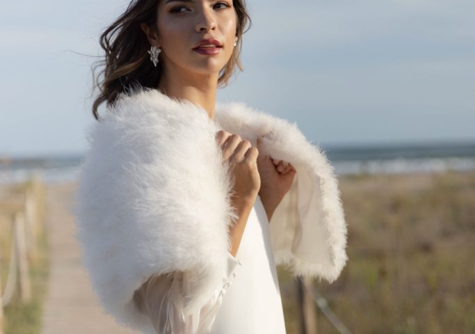 chica con vestido de novia posando en la playa