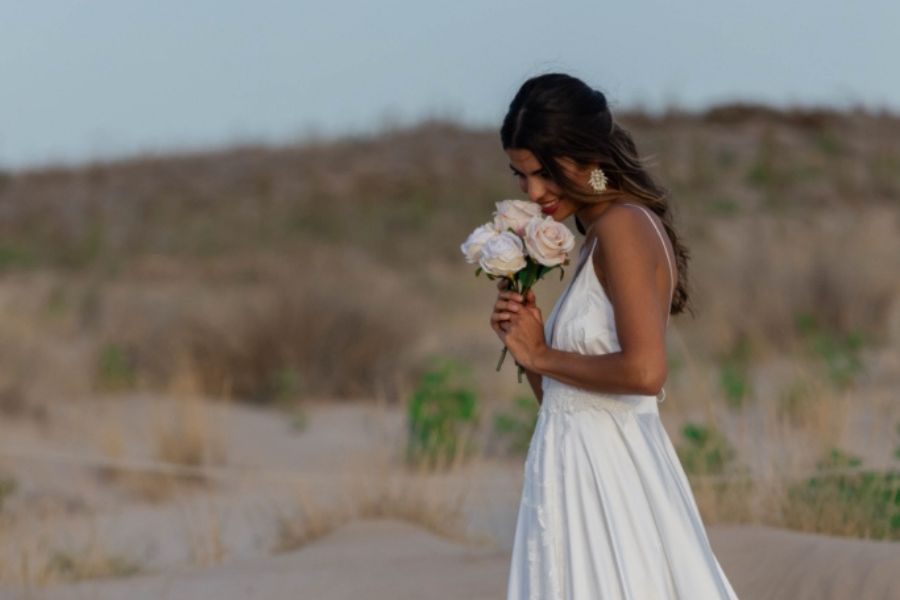 chica con vestido de novia oliendo flores