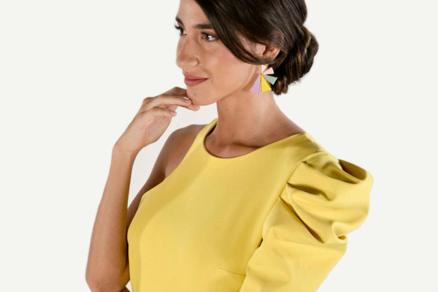 chica luce un vestido en tono amarillo con hombro descubierto